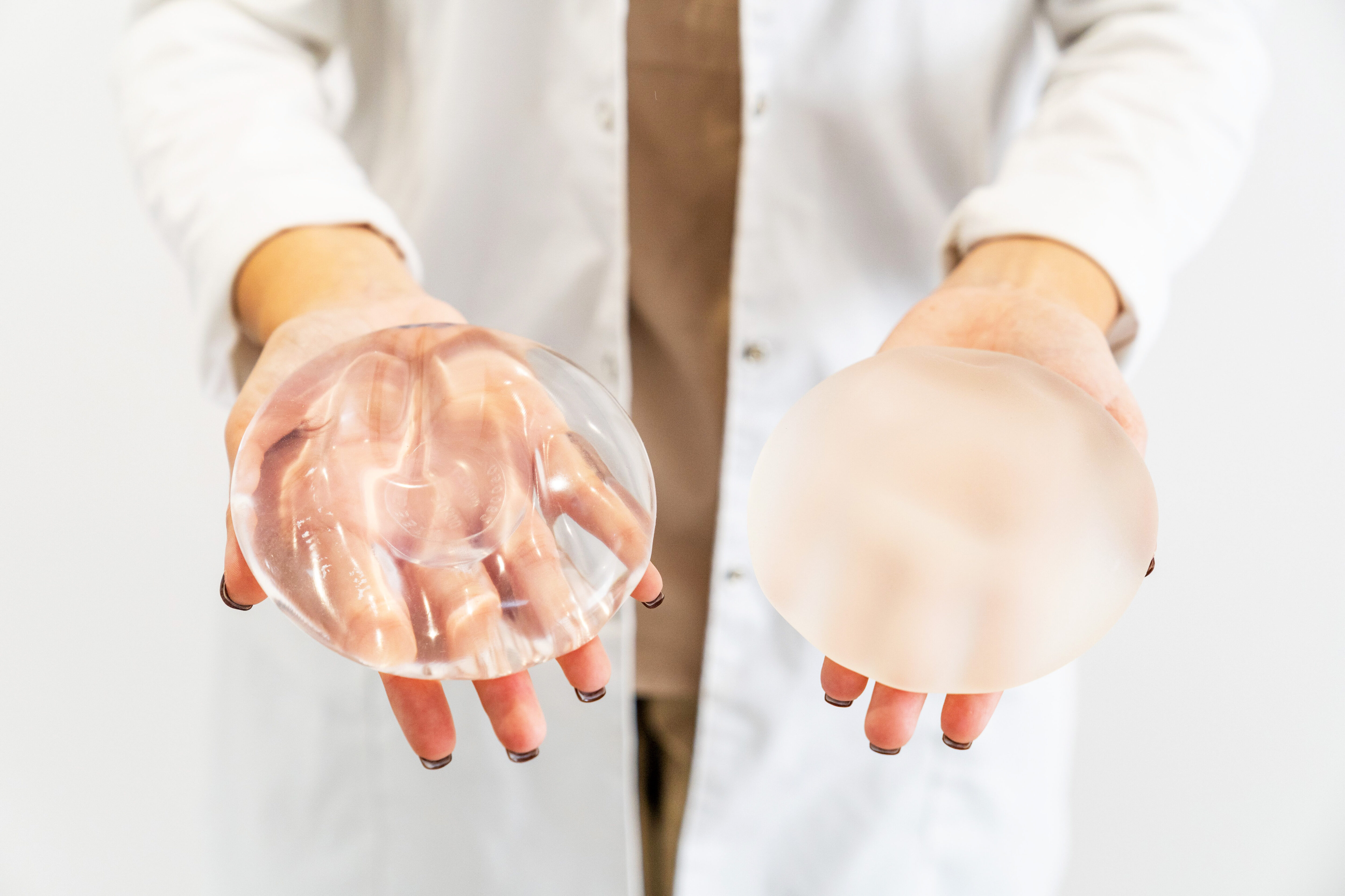 surgeon holding silicone and saline breast implants