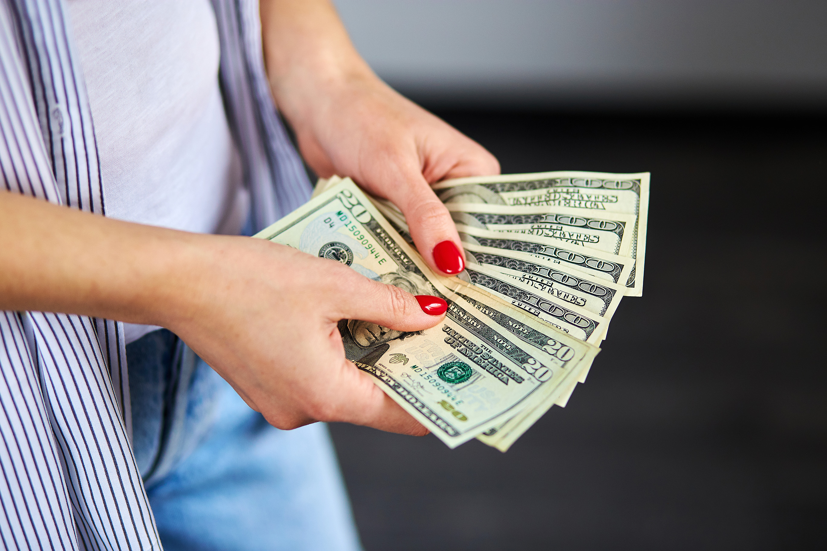 woman with red nails holding cash