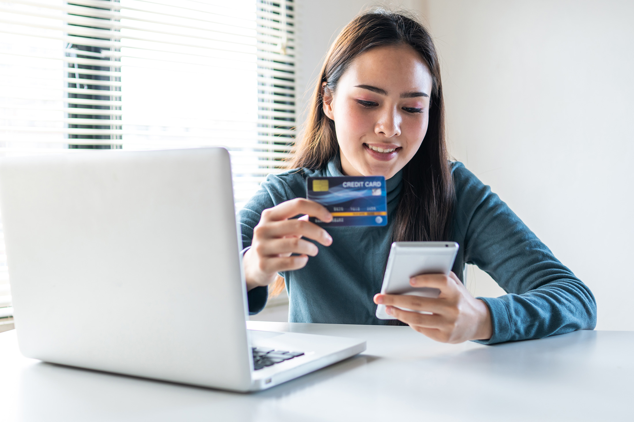 smiling woman paying with card on phone